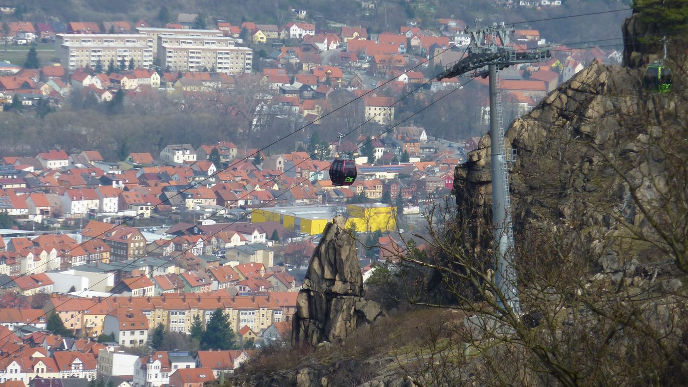 Blick vom Hexentanzplatz über Thale, im Vordergrund die Felsen am Talausgang und eine Gondel der Bodetal-Seilbahn